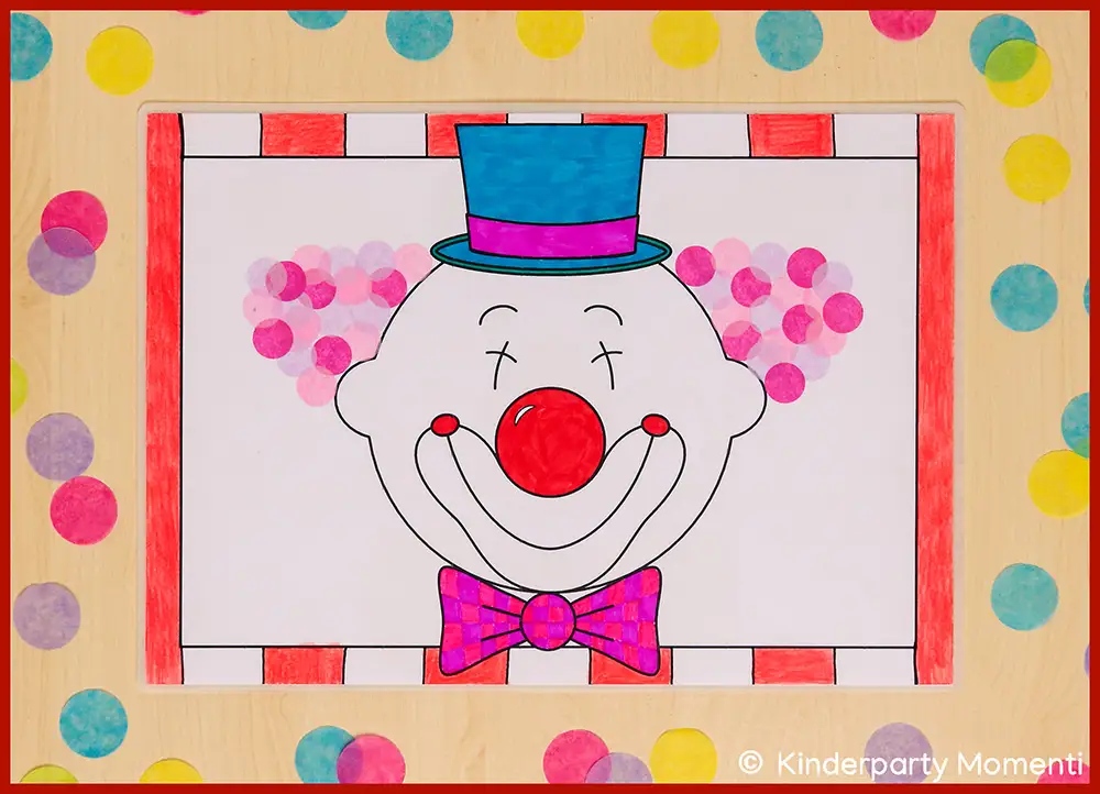 Bunt Tischset mit einem Clownsgesicht, das einen blauen Zylinderhut, eine rote Nase und eine pink-karierte Fliege trägt, umgeben von bunten Punkten auf hellem Hintergrund